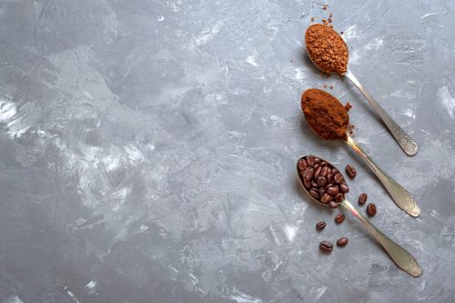 Coffee beans, ground coffee and instant coffee in the spoons on a gray background. Top view, copy space.